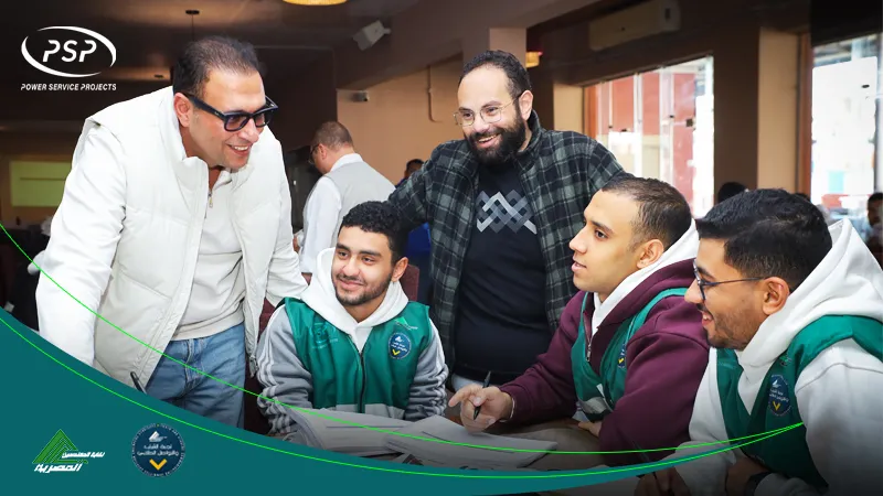 A group of young trainees sit together during a PSP workshop while two mentors stand beside them, engaging in a friendly and supportive discussion.