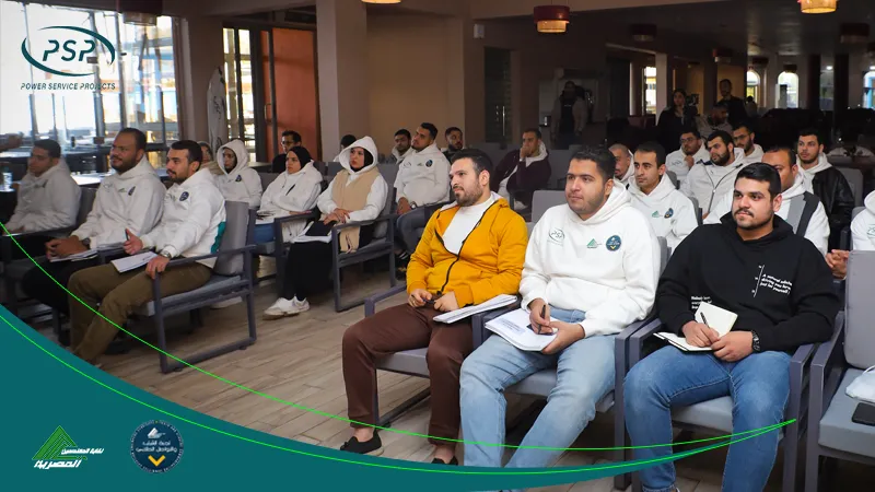 A classroom full of PSP trainees, wearing white branded hoodies, sit attentively with notebooks during a practical engineering training session.